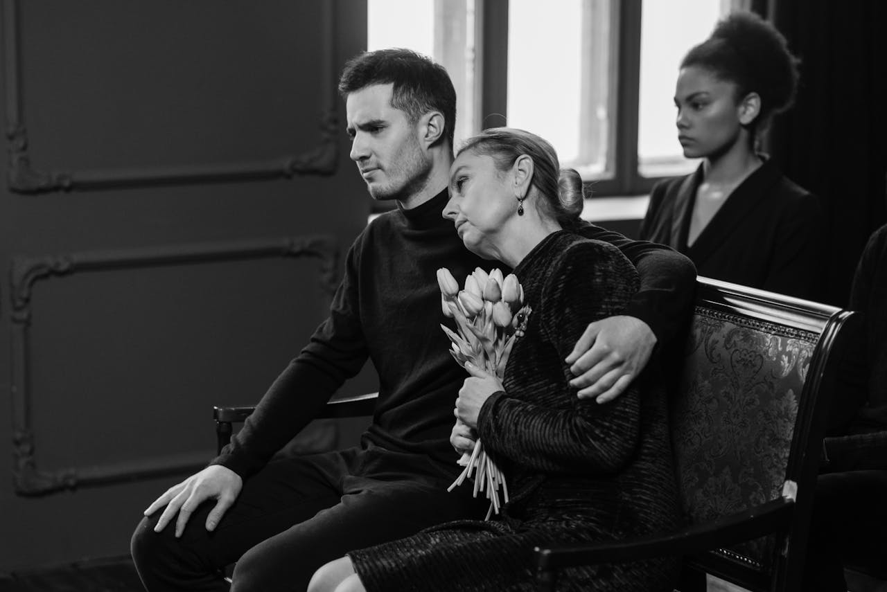 A somber black and white image capturing a grieving family at a funeral.